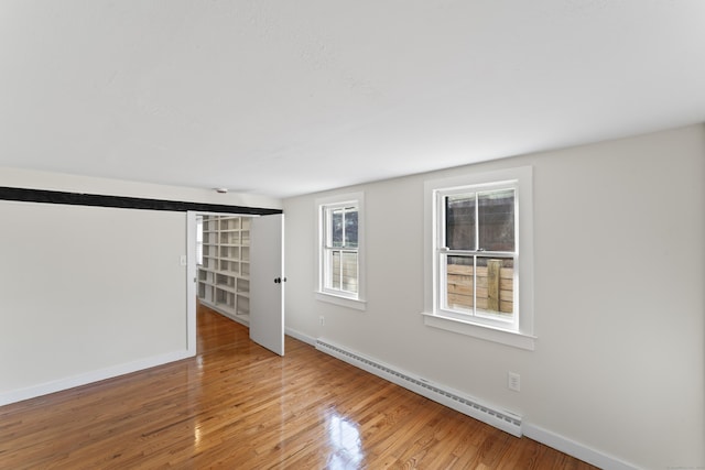 empty room featuring hardwood / wood-style floors and baseboard heating