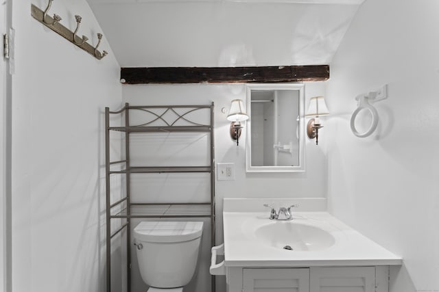 bathroom featuring beamed ceiling, vanity, and toilet