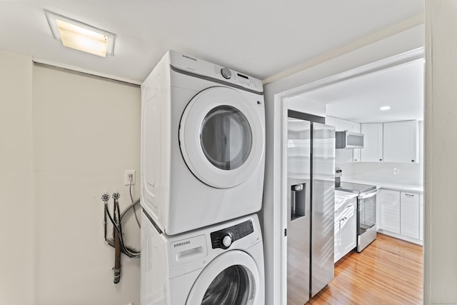 washroom featuring light wood-type flooring and stacked washer / dryer