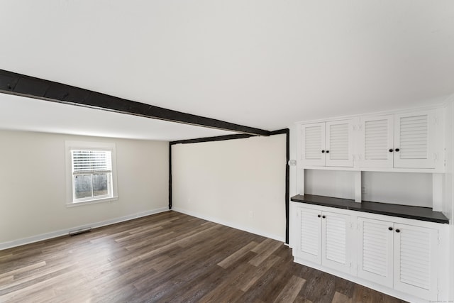 unfurnished living room with beamed ceiling and wood-type flooring