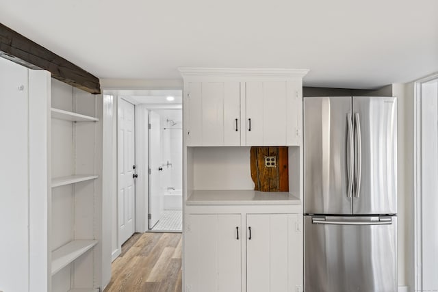 kitchen with light wood-type flooring, white cabinetry, and stainless steel refrigerator