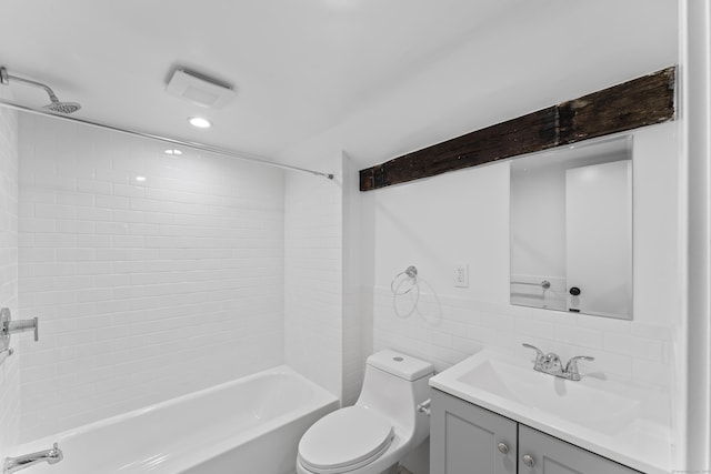 full bathroom featuring tiled shower / bath, vanity, tile walls, and toilet