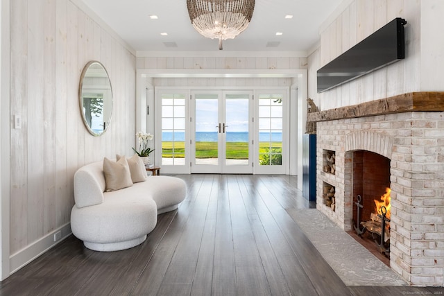 sitting room with dark wood-style floors, french doors, a brick fireplace, and wooden walls