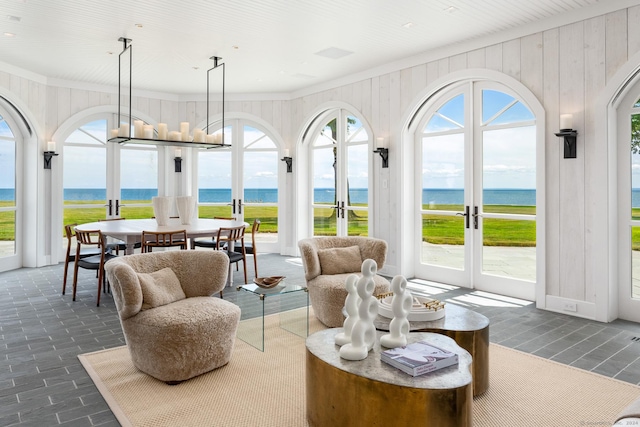sunroom featuring french doors and a water view