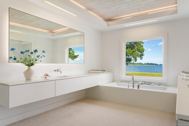 bathroom featuring wooden ceiling, a healthy amount of sunlight, a water view, and a tray ceiling