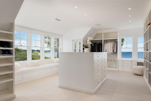 walk in closet with light colored carpet and lofted ceiling