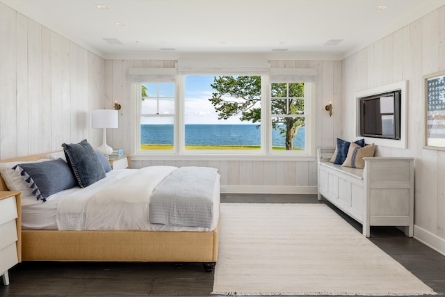 bedroom with a water view, wood walls, baseboards, and wood finished floors