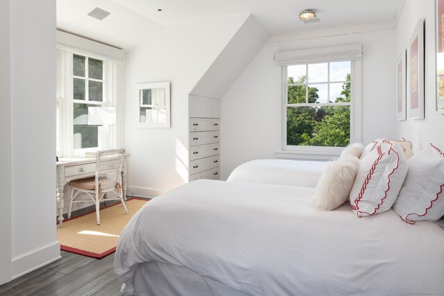 bedroom with dark hardwood / wood-style floors, vaulted ceiling, and multiple windows