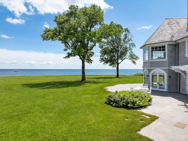 view of yard with a patio area, french doors, and a water view