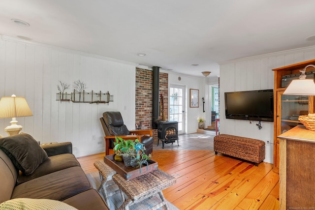 living room featuring ornamental molding, a wood stove, and light wood-type flooring