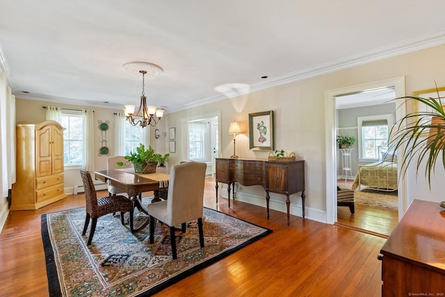 dining space with ornamental molding, plenty of natural light, hardwood / wood-style floors, and an inviting chandelier