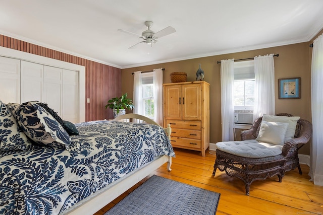 bedroom with hardwood / wood-style flooring, crown molding, ceiling fan, and a closet