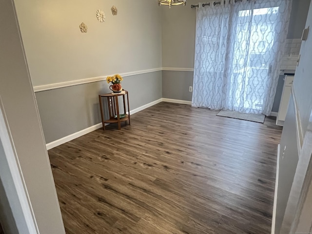 empty room featuring dark hardwood / wood-style flooring and a chandelier