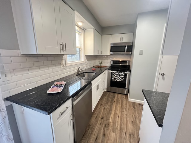 kitchen featuring white cabinets, stainless steel appliances, dark stone countertops, and sink