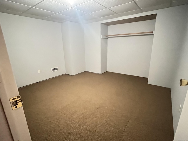 unfurnished bedroom with carpet flooring, a closet, and a drop ceiling