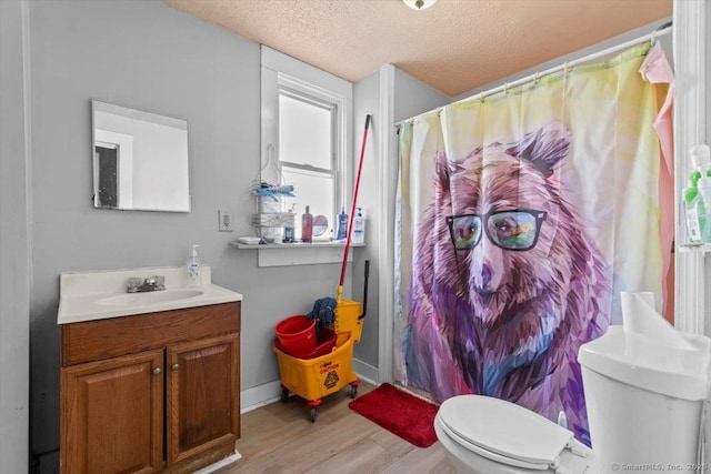 bathroom with vanity, toilet, a textured ceiling, walk in shower, and wood-type flooring