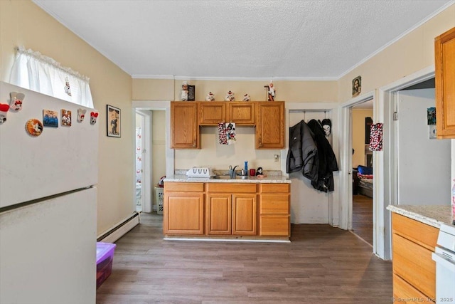 kitchen with sink, a baseboard heating unit, white fridge, wood-type flooring, and a textured ceiling