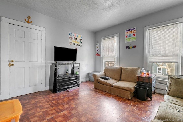 living room with dark parquet floors, a healthy amount of sunlight, and a textured ceiling