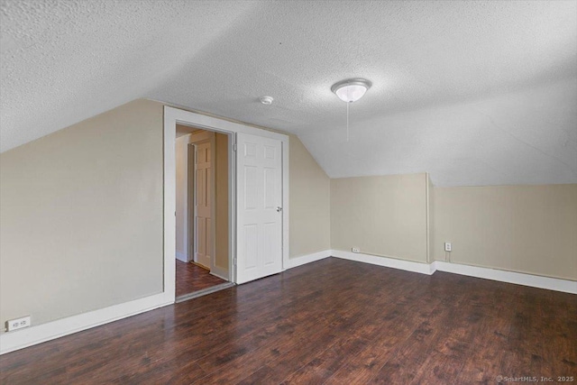 additional living space with a textured ceiling, dark wood-type flooring, and lofted ceiling