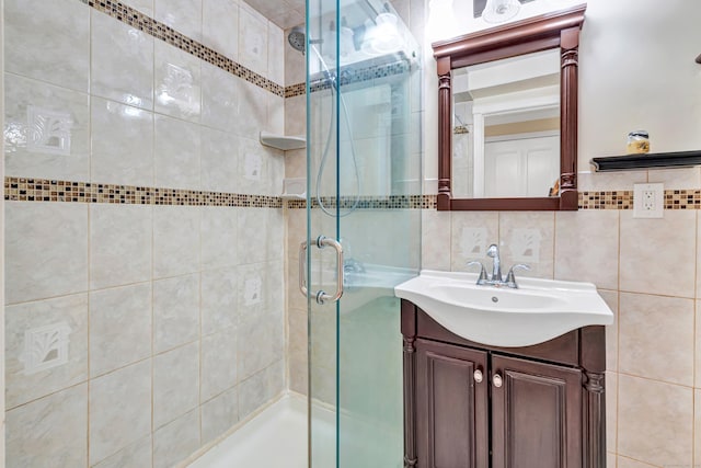 bathroom featuring backsplash, vanity, an enclosed shower, and tile walls