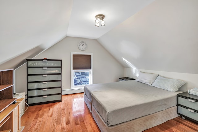 bedroom featuring light hardwood / wood-style floors, lofted ceiling, and a baseboard heating unit