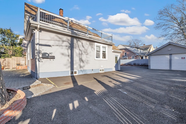 view of side of property featuring a garage, a balcony, and an outdoor structure