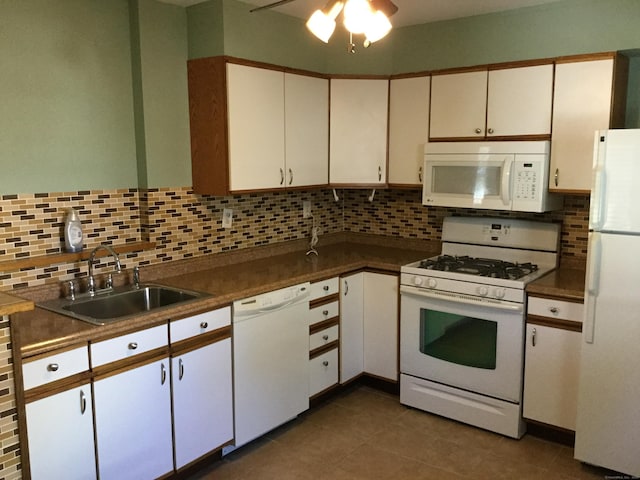 kitchen with backsplash, white appliances, sink, dark tile patterned flooring, and white cabinetry