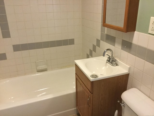 bathroom featuring tasteful backsplash, a bathtub, vanity, tile walls, and toilet