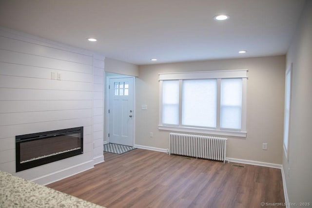 entrance foyer with hardwood / wood-style floors, a large fireplace, and radiator