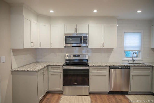 kitchen with backsplash, sink, stainless steel appliances, and light hardwood / wood-style floors