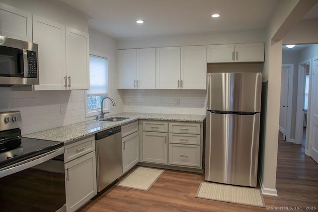 kitchen featuring white cabinetry, sink, hardwood / wood-style floors, decorative backsplash, and appliances with stainless steel finishes