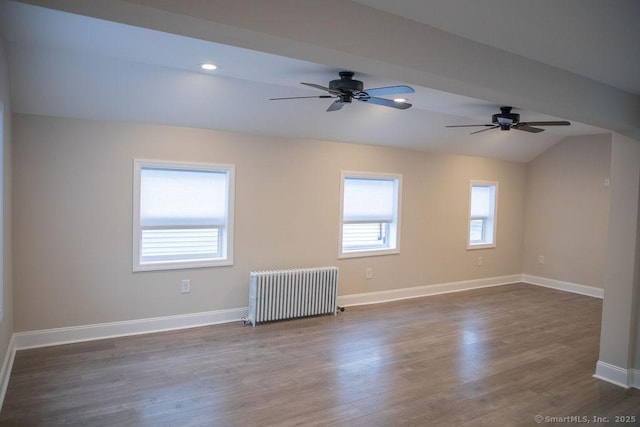 empty room with ceiling fan, dark hardwood / wood-style flooring, radiator, and vaulted ceiling