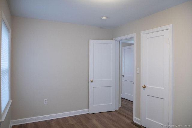 unfurnished bedroom with dark hardwood / wood-style floors and multiple windows