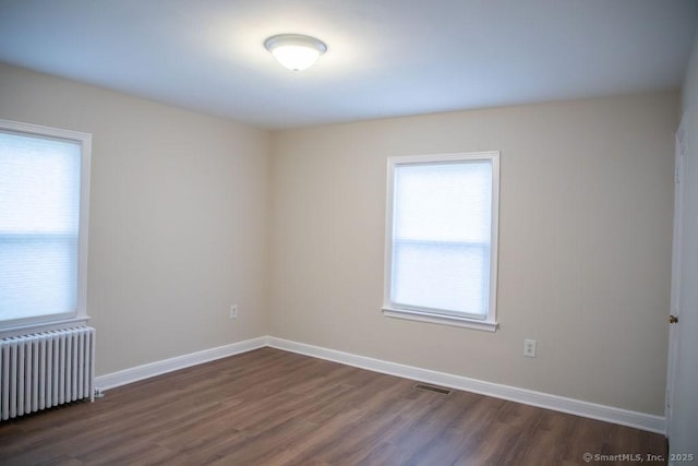 empty room featuring radiator and dark wood-type flooring