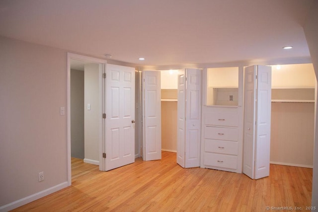 unfurnished bedroom featuring a spacious closet, a closet, and light wood-type flooring