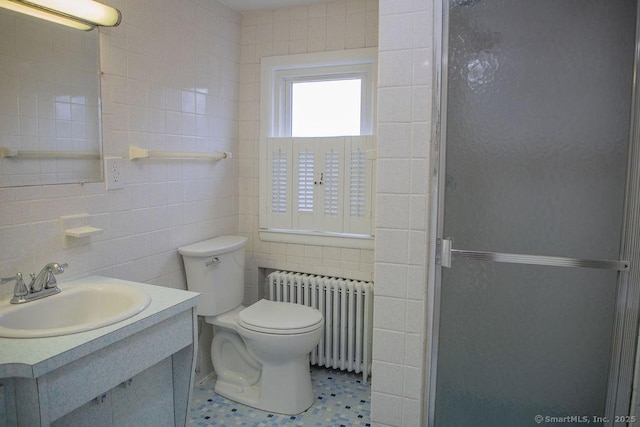 bathroom featuring walk in shower, vanity, tile walls, radiator heating unit, and toilet