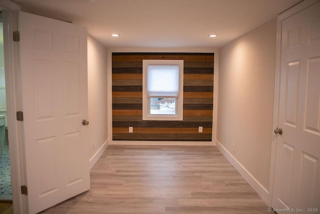 hallway with light wood-type flooring and wooden walls