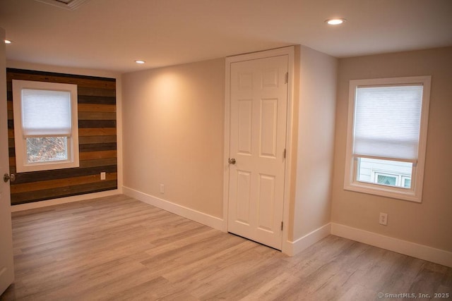 spare room with light wood-type flooring and wooden walls