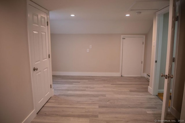 corridor with light wood-type flooring and baseboard heating