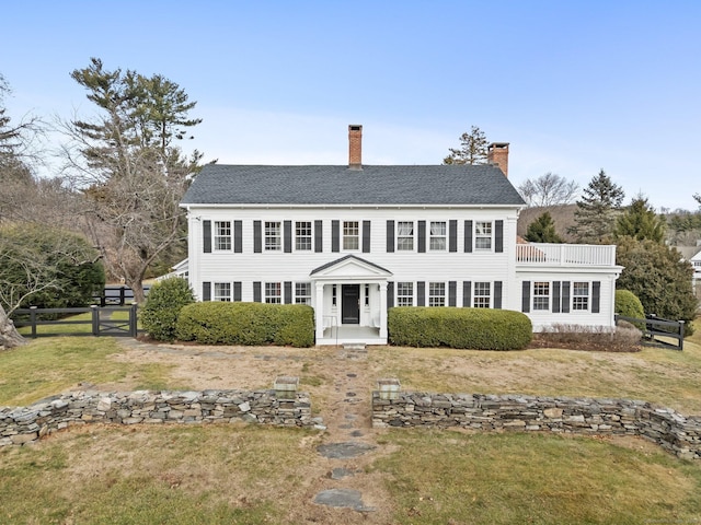 colonial-style house featuring a balcony and a front yard