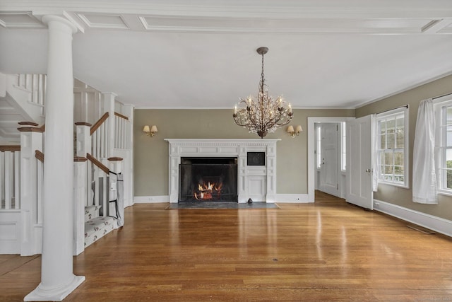 unfurnished living room with an inviting chandelier, ornamental molding, hardwood / wood-style flooring, a high end fireplace, and decorative columns