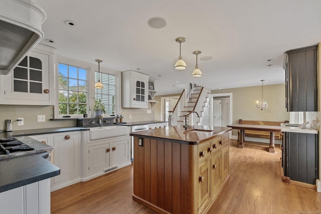 kitchen featuring white cabinetry, sink, and a kitchen island with sink