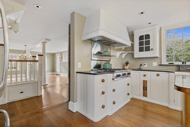 kitchen with white cabinetry, premium range hood, stainless steel gas stovetop, and light hardwood / wood-style floors