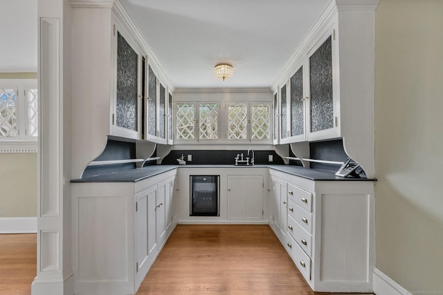 kitchen featuring white cabinetry, ornamental molding, a wealth of natural light, and wine cooler