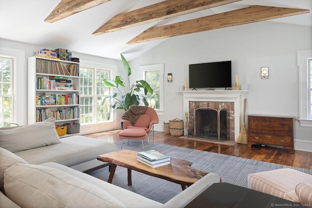 living room featuring a fireplace, vaulted ceiling with beams, baseboards, and wood finished floors