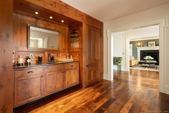 bar with bar, dark wood-type flooring, and a sink