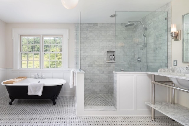 full bathroom featuring a soaking tub, wainscoting, a decorative wall, and a walk in shower