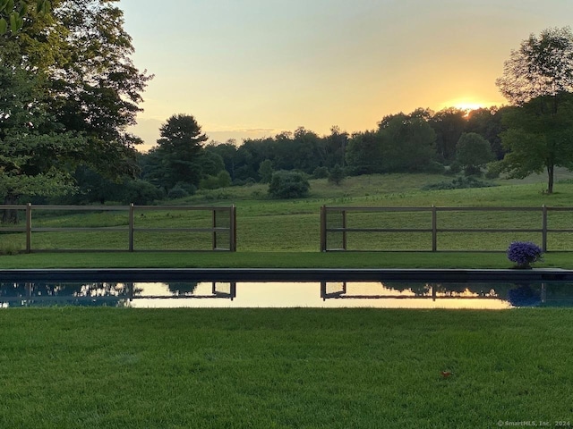 view of home's community with a water view, fence, and a yard