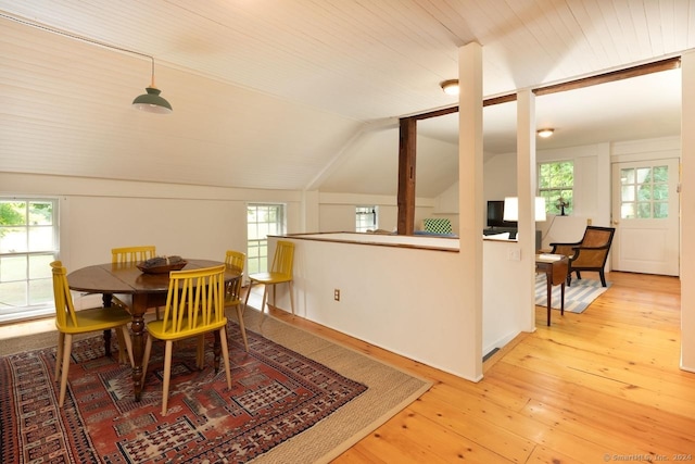 dining room with light wood-type flooring, a healthy amount of sunlight, and lofted ceiling