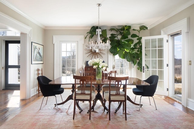 dining space featuring baseboards, an inviting chandelier, wood finished floors, and crown molding